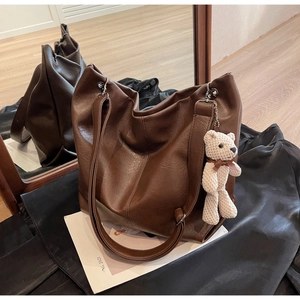 Close-up of brown PU leather tote bag texture with cute knit bear charm decoration