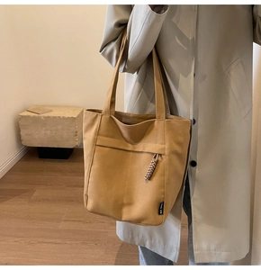 Detalle del bolso tote de lona caqui con bolsillo frontal y tirador de cremallera
