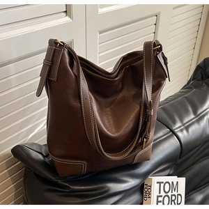 Détail d'un sac seau hobo marron avec surpiqûres contrastées et boucles dorées
