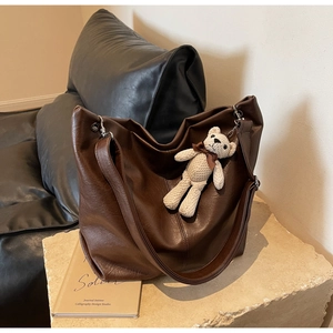 Detail of dark brown faux leather tote with textured finish and a cute knitted bear charm