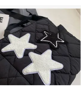 Detailansicht der schwarzen Stepptasche mit Plüschstern-Patches und Gittersteppung