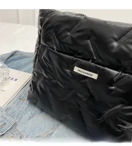 Detail of black quilted puffer tote fabric with glossy finish and white fashion label