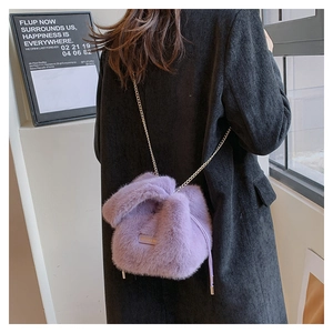 Detail der lila flauschigen Eimertasche mit Metallkette über einem dunklen Mantel