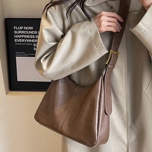 Deep brown vintage tote bag with adjustable metallic buckle on model's shoulder