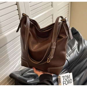 Gros plan d'un sac seau en cuir marron foncé avec coutures contrastées et boucle dorée