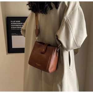 Detail of vintage brown bucket bag with wide woven strap and metal buckle accent