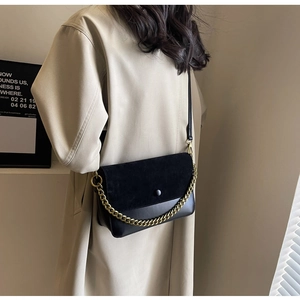 Detail of black crossbody bag with gold chain strap and vintage suede leather texture