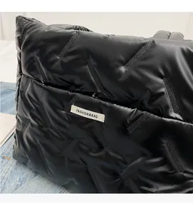 Close-up of black quilted puffer tote bag featuring fashion label and glossy texture