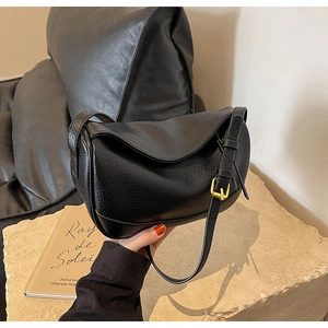 Detail view of black lychee grain leather crossbody bag with elegant gold metal buckle
