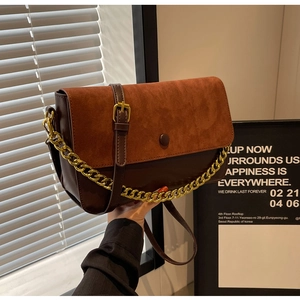 Detail of vintage brown leather crossbody bag with suede flap and gold chain strap