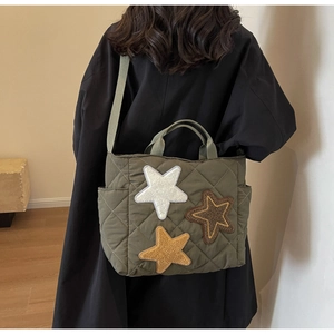 Detail der olivgrünen gesteppten Canvas-Tasche mit Stern-Patches und verstellbarem Gurt