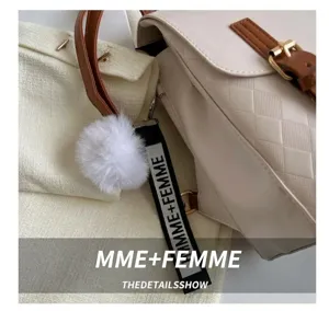 Détail d'un sac à dos beige matelassé avec sangles en cuir brun et breloque en fourrure