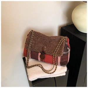 Detail of red-brown plaid tote bag with faux shearling flap and gold chain strap