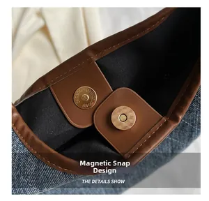 Macro detail of magnetic buckle closure on a denim tote bag with leather piping