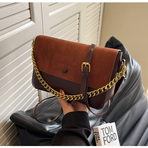 Close-up of retro crossbody bag with brown suede flap and golden chain detail