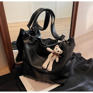 Detailed view of black PU leather tote bag with a cute white knit bear charm accessory