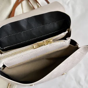 Detailansicht der Innenfächer und des glatten Metallreißverschlusses der beige gewebten Tasche