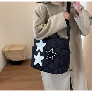 Detail der schwarzen gesteppten Shopper Tasche mit Stern-Patches und Schultergurt