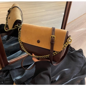 Detail of retro color-block crossbody bag featuring brown leather and suede flap texture