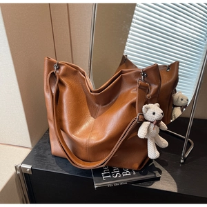 Brown faux leather tote bag with white knitted bear charm and large storage capacity
