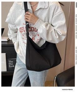 Sac bandoulière minimaliste noir en nylon en forme de croissant porté par le mannequin