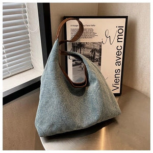 Detailed view of light blue denim tote with quilted pattern and brown leather straps