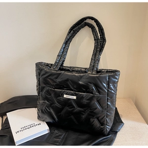 Macro detail of black quilted tote bag showing rhombus stitching and fashion label