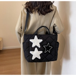 Detail der schwarzen Stepp-Tote-Bag mit Stern-Patches und verstellbarem Umhängeriemen
