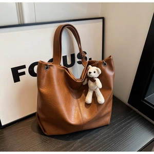 Detail of soft brown PU leather tote bag with vintage texture and white bear charm