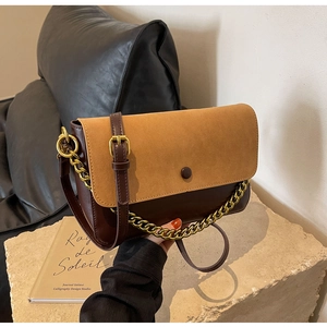 Detail of color-block leather and suede shoulder bag with gold chain and button