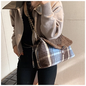 Detail of plaid tote bag with plush faux fur trim and gold chain strap worn by model