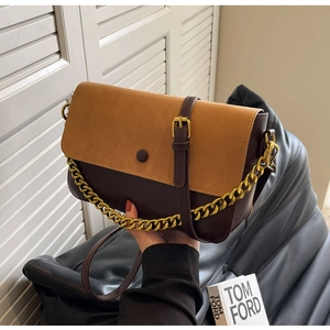 Detail view of contrast color crossbody bag with gold chain and faux suede flap