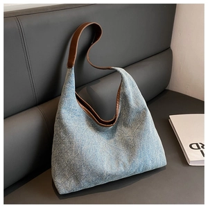 Detailed shot of denim tote bag featuring quilted diamond pattern and brown leather straps