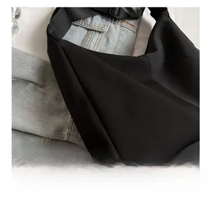 Détail de la bandoulière réglable et de la boucle métallique du sac hobo en toile noire robuste