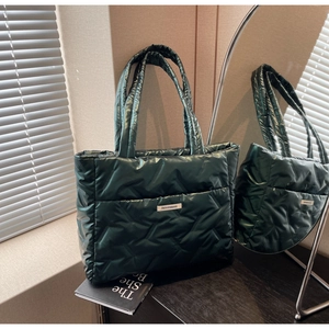 Detail of dark green quilted tote bag with smooth nylon texture and fashion label