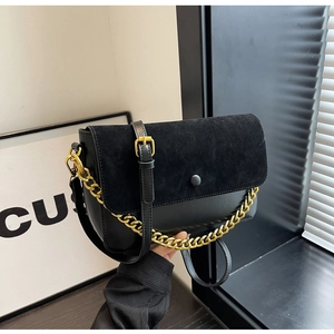 Close-up of black crossbody bag featuring mixed textures and a gold chunky chain strap