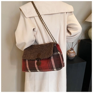 Detail of red plaid tote bag with faux fur flap and gold chain strap on model