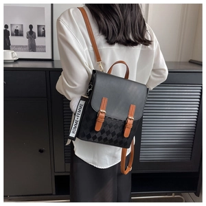 Detail des karierten Patchwork-Rucksacks mit braunen Riemen und weißem Bommel