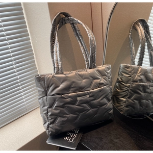 Macro detail of silver quilted tote bag with metallic gloss and logo tag texture