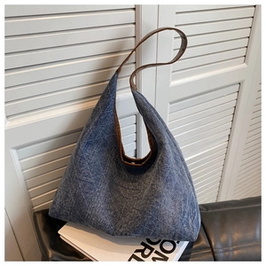 Detail view of denim tote bag with quilted diamond pattern and brown leather straps
