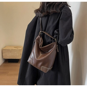 Détail d'un grand sac hobo en cuir marron avec surpiqûres blanches sur un mannequin