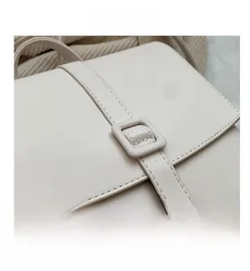 Dettaglio dello zaino vintage beige con fibbia quadrata, cuciture e texture in pelle