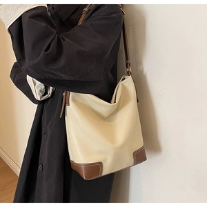 Détail du grand sac seau crème et marron montrant la texture du cuir et la bandoulière