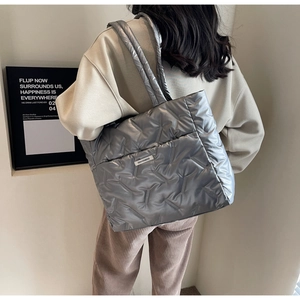 Silver quilted tote bag shown in a lifestyle view featuring puffy diamond patterns