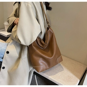 Détail du grand sac seau en cuir marron foncé avec coutures blanches décoratives