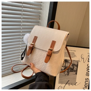 Detail eines weißen Stepprucksacks mit braunen Riemen und Plüschkugel-Accessoire