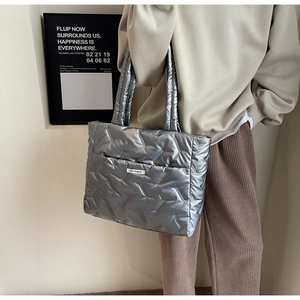 Detail of silver quilted tote bag showing V-shape stitching and fashion label on shoulder