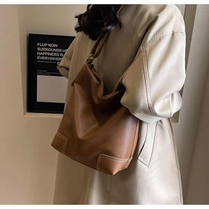 Détail d'un sac seau en cuir marron avec coutures contrastées blanches et texture mate