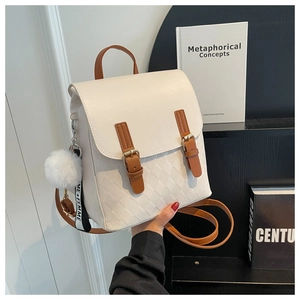 Detail des cremefarbenen Rucksacks mit Rautensteppung und modischem Plüsch-Anhänger