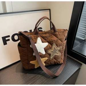 Nahaufnahme der braunen gesteppten Canvas-Tasche mit Plüschsternen und praktischen Seitentaschen